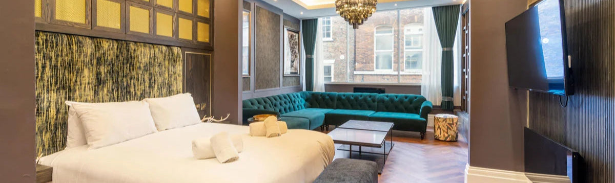 Luxurious bedroom with a bed, green sofa, and chandelier.